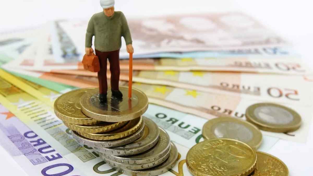 Figura de un pensionista sobre monedas y billetes de euro para ilustrar las pensiones contributivas y no contributivas