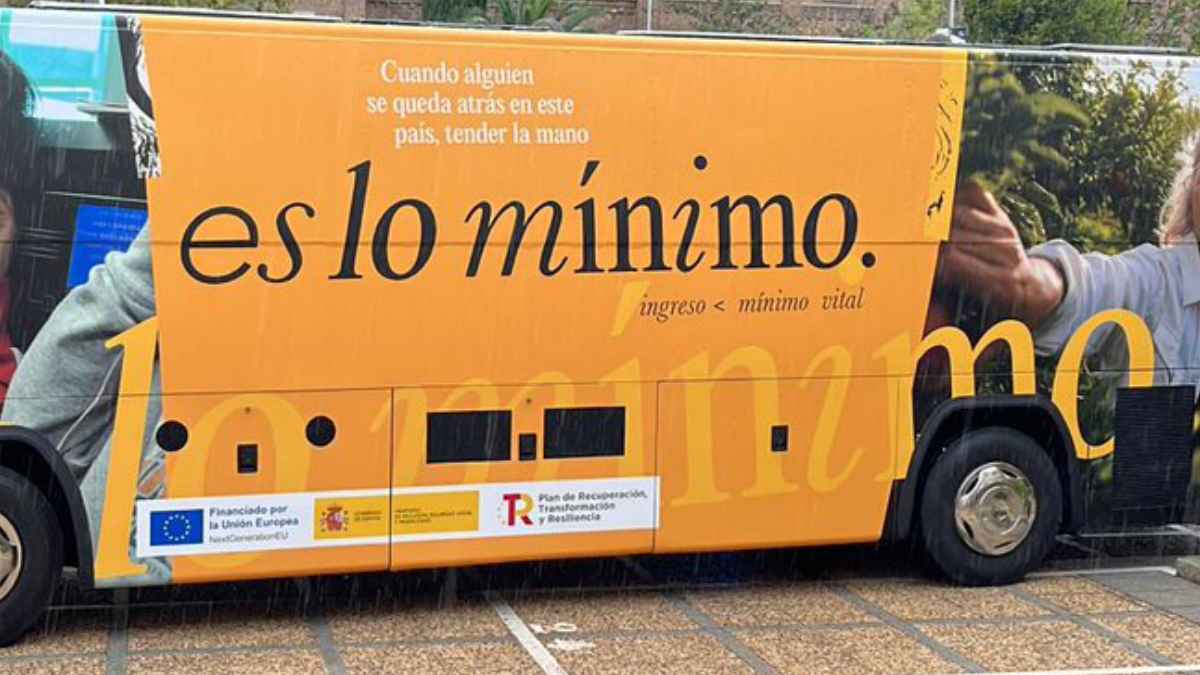 Autobús informativo del Ingreso Mínimo Vital con el lema “es lo mínimo” usado en una noticia sobre revisión del padrón y devolución del IMV.
