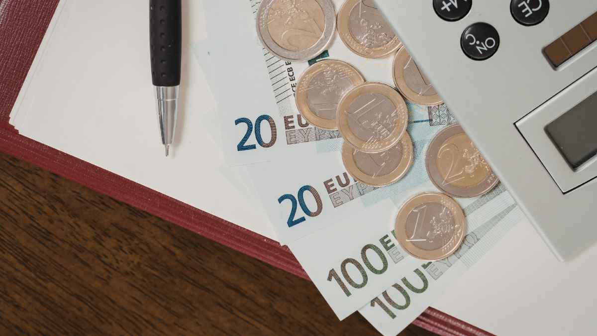 Billetes y monedas de euro junto a una calculadora representando el ahorro fiscal y las deducciones para autónomos que trabajan fuera de casa