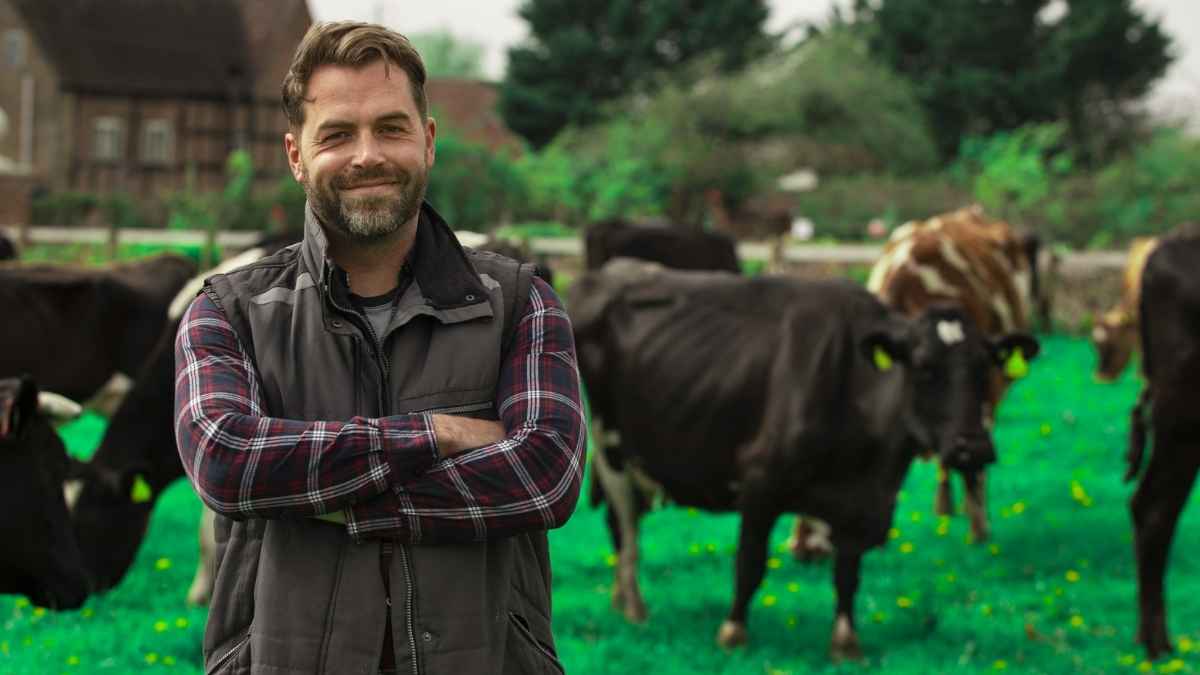 Ganadero en una granja con vacas al fondo, ejemplo de ganadería extensiva y dependencia de ayudas PAC