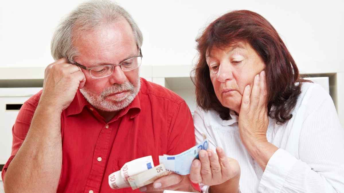 Una pareja de mayores revisa billetes de euro en casa ante la posible suspensión del subsidio para mayores de 52 años