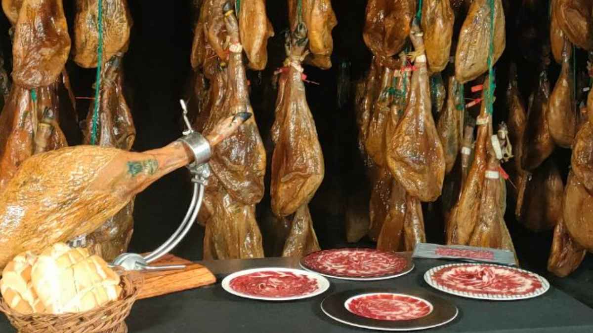 Jamones curados colgados y platos de jamón ibérico en una imagen sobre el nuevo etiquetado de alimentos en el supermercado