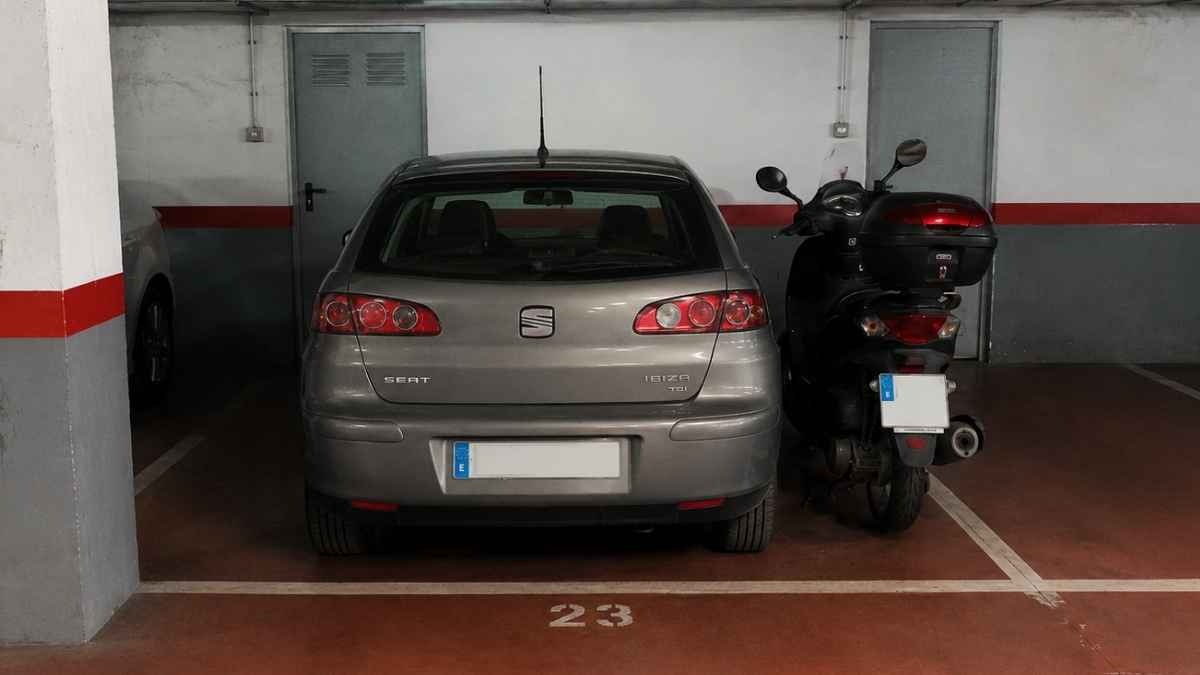 Coche y moto aparcados en la misma plaza de garaje comunitario en España