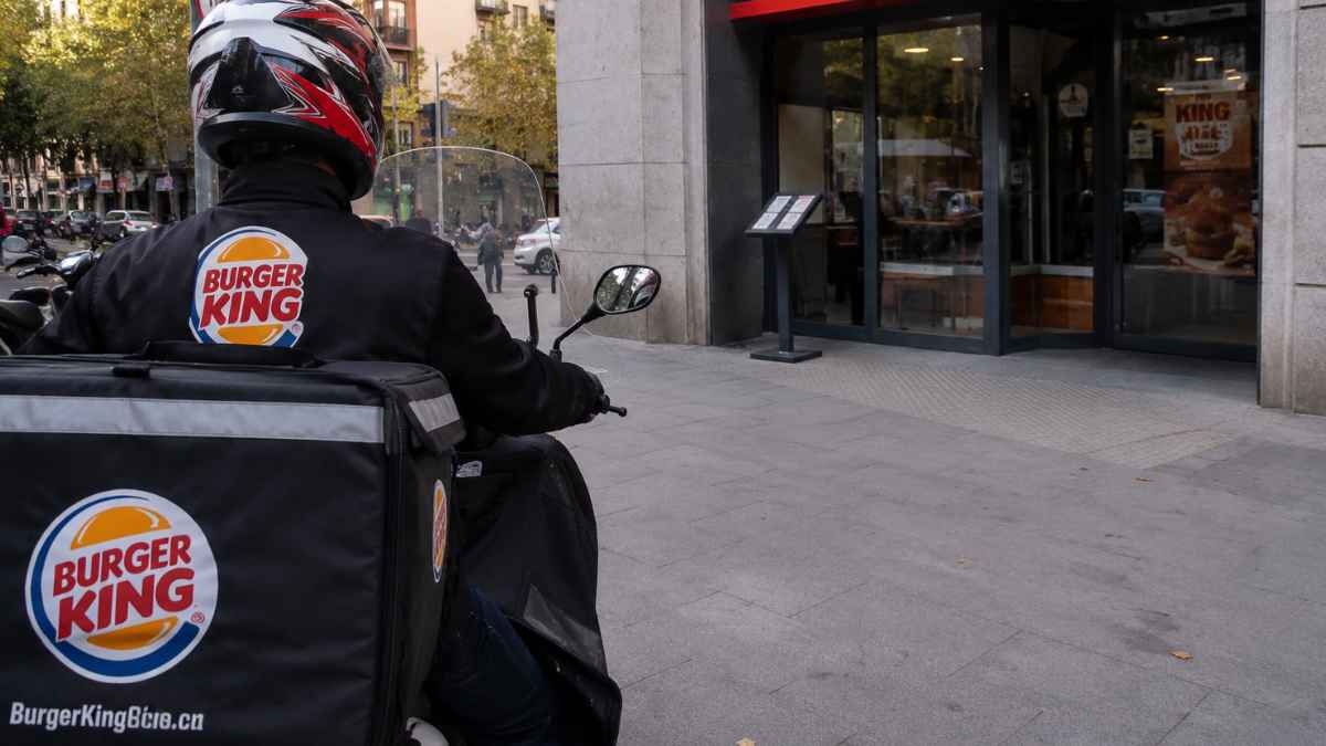 Repartidor de Burger King en moto frente a un restaurante tras la sentencia que declara improcedente su despido por no llevar la equipación completa