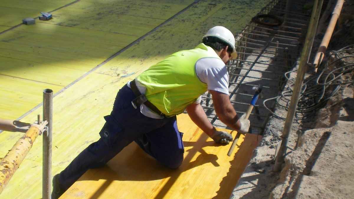 Albañil trabajando en una obra de construcción mientras instala material en una estructura de hormigón