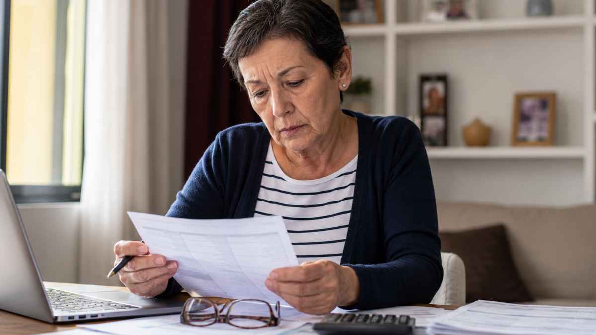 Mujer revisa su vida laboral y documentos de pensión junto a un portátil y una calculadora