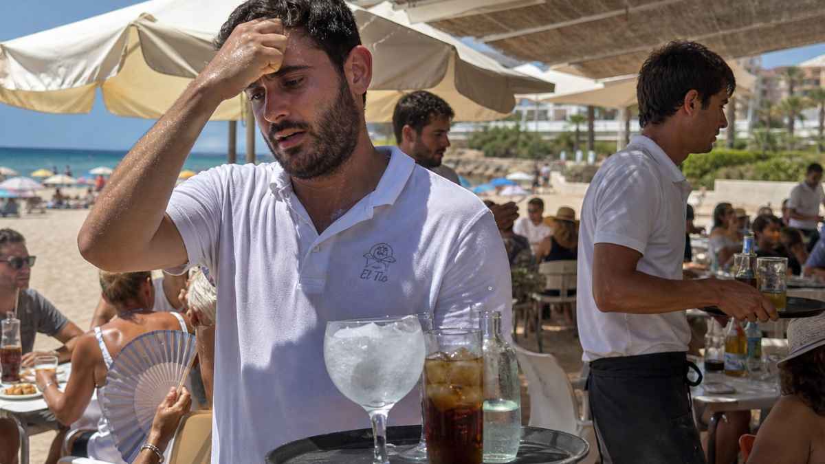 camarero trabajando en terraza de bar de playa durante ola de calor con altas temperaturas