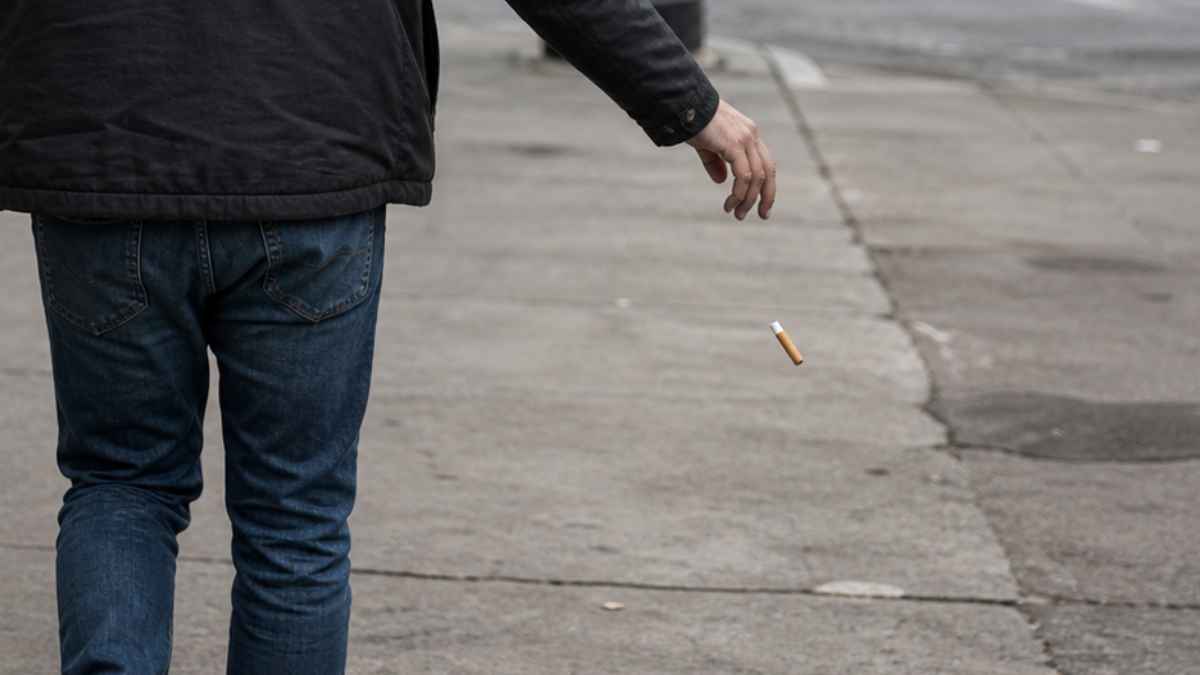 Hombre tirando una colilla al suelo en una calle de Valencia