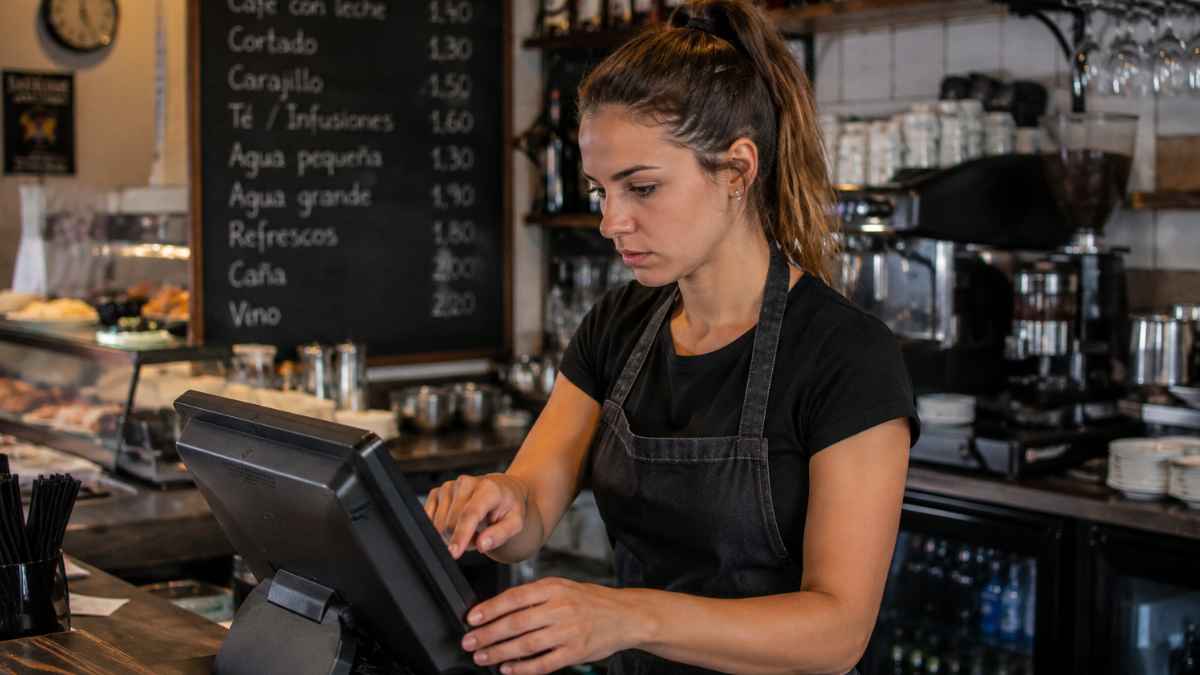 Camarera utilizando la caja registradora en un bar de Asturias durante su jornada laboral
