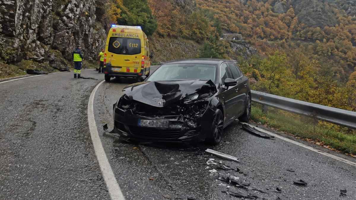 Coche accidentado en una carretera de montaña con una ambulancia y servicios de emergencia en el lugar