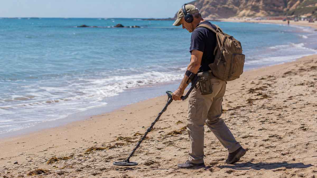 Persona utilizando un detector de metales en una playa de Andalucía donde la Junta endurece las sanciones para proteger el patrimonio arqueológico.