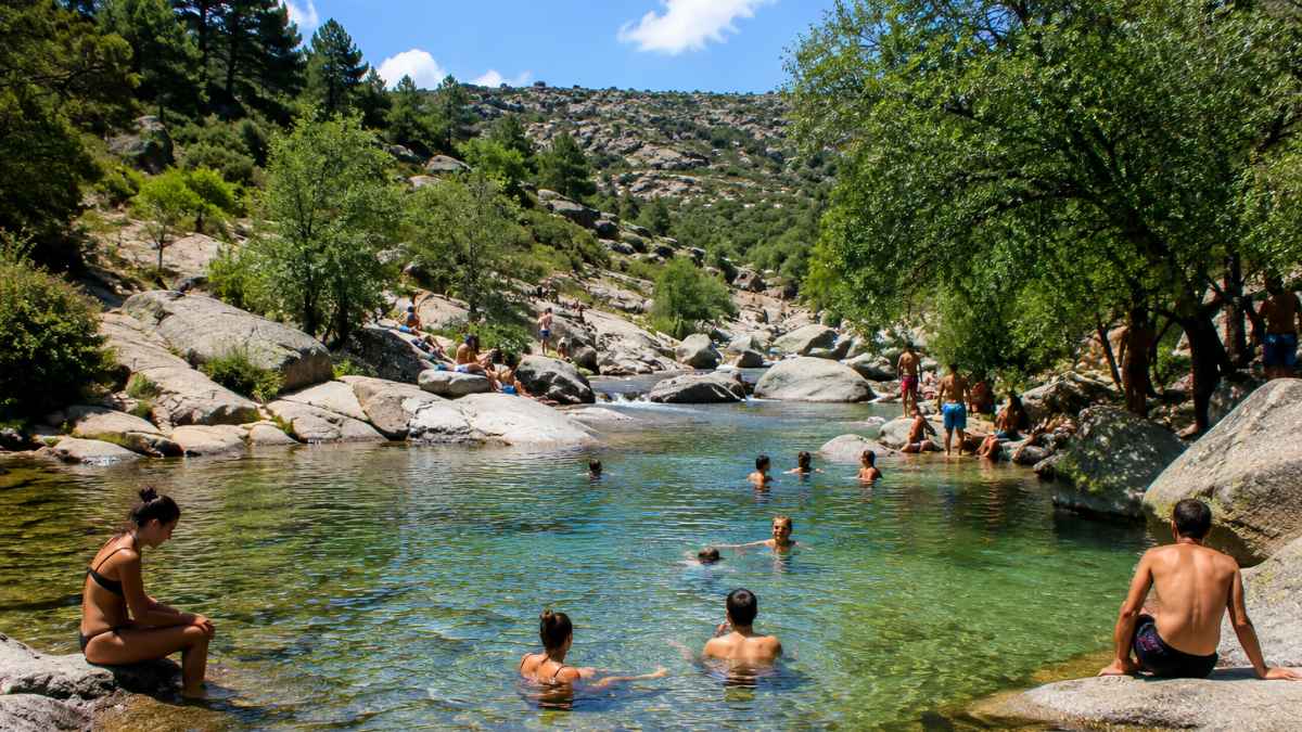 Personas bañándose en una charca natural de la Sierra de Guadarrama, una de las zonas donde la Comunidad de Madrid refuerza la vigilancia durante el verano.