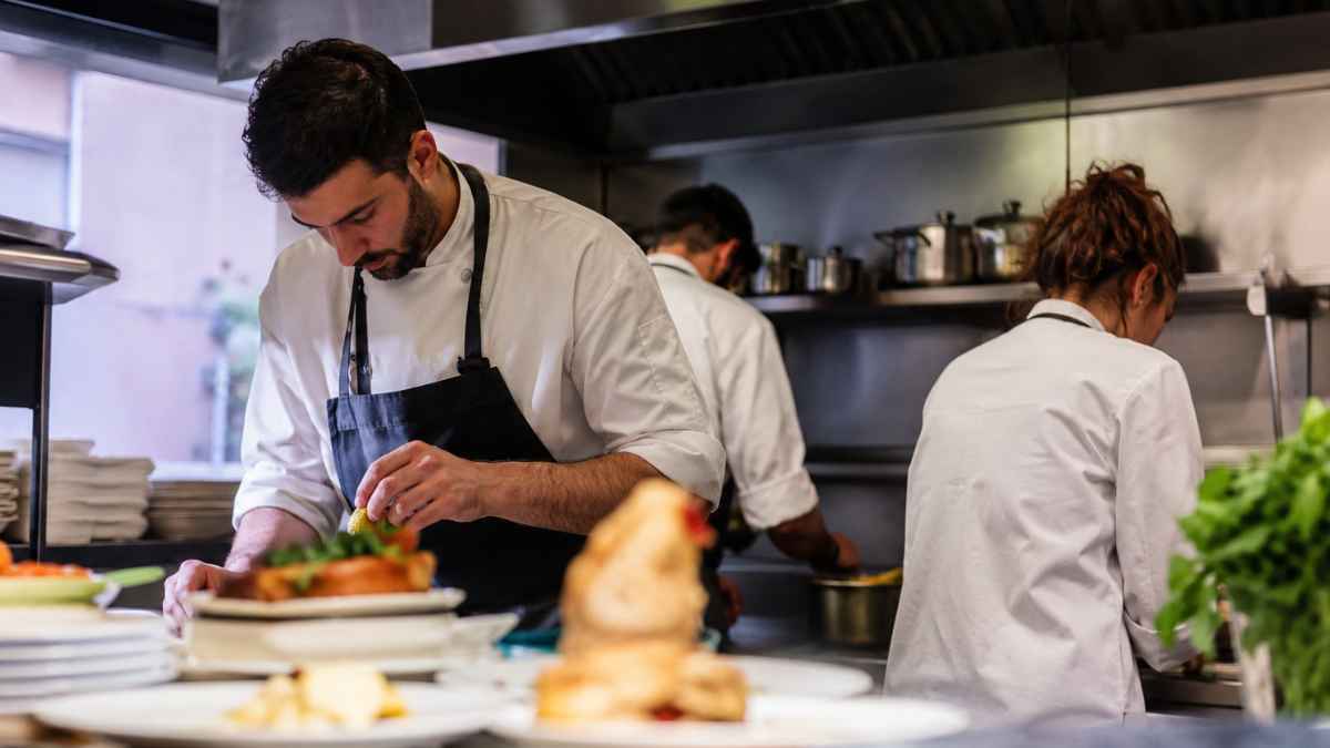Camareros y cocineros trabajando en una cocina de hostelería durante un turno largo