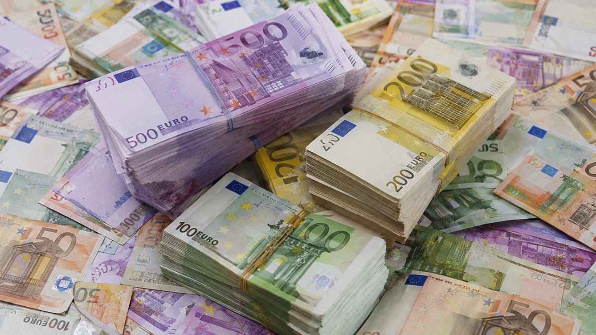 Billetes de euro apilados y repartidos sobre una mesa como símbolo de una herencia vacante que pasa al Estado
