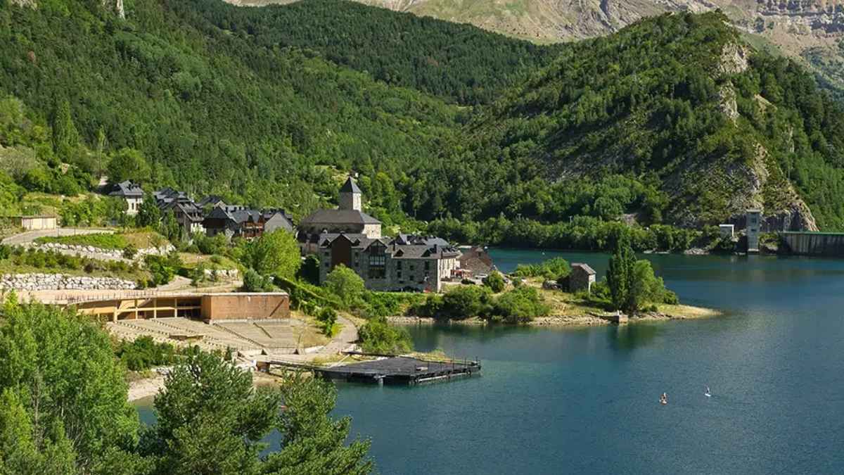 Lanuza, pueblo del Pirineo aragonés con casas de pizarra junto al embalse y el escenario flotante de Pirineos Sur