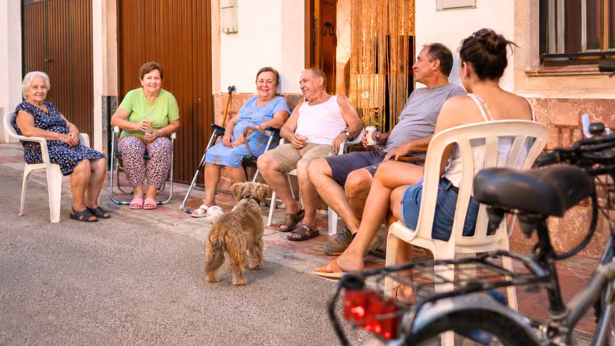 Vecinos sentados en sillas a la puerta de casa durante una tarde de verano en un pueblo de España
