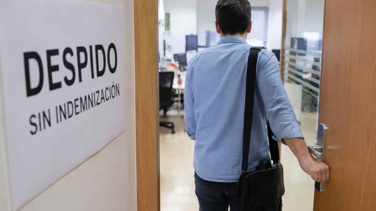 Trabajador saliendo de una oficina mientras un cartel indica despido sin indemnización