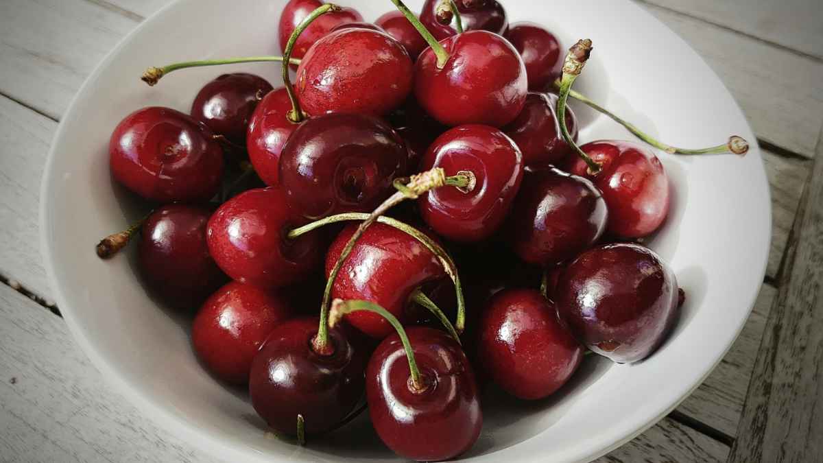 Cerezas frescas con rabito en un plato blanco listas para conservar en la nevera