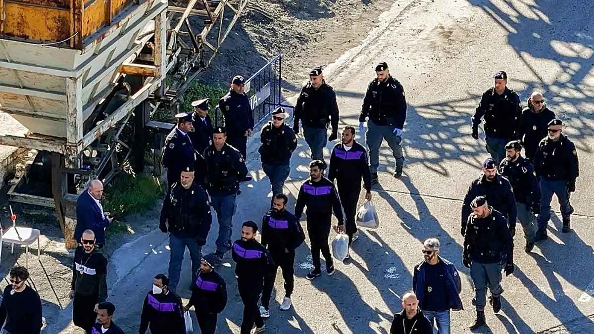 Migrantes irregulares escoltados por agentes de policía durante un operativo de traslado en un centro de detención