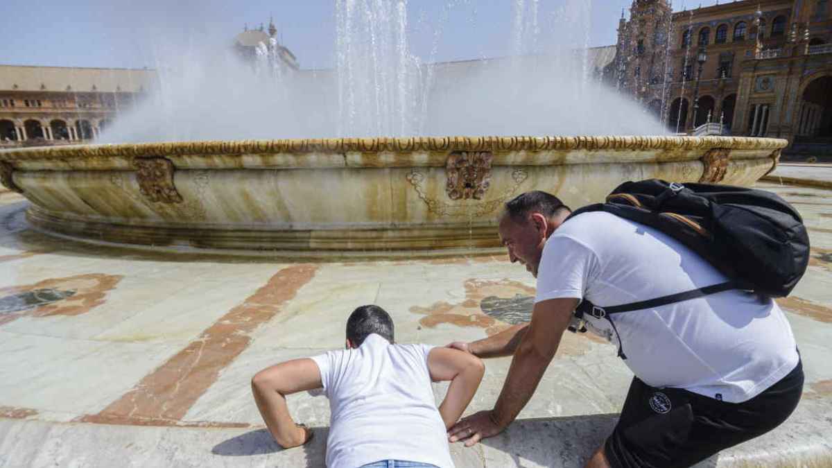 Dos personas se refrescan en una fuente durante una jornada de calor extremo en España