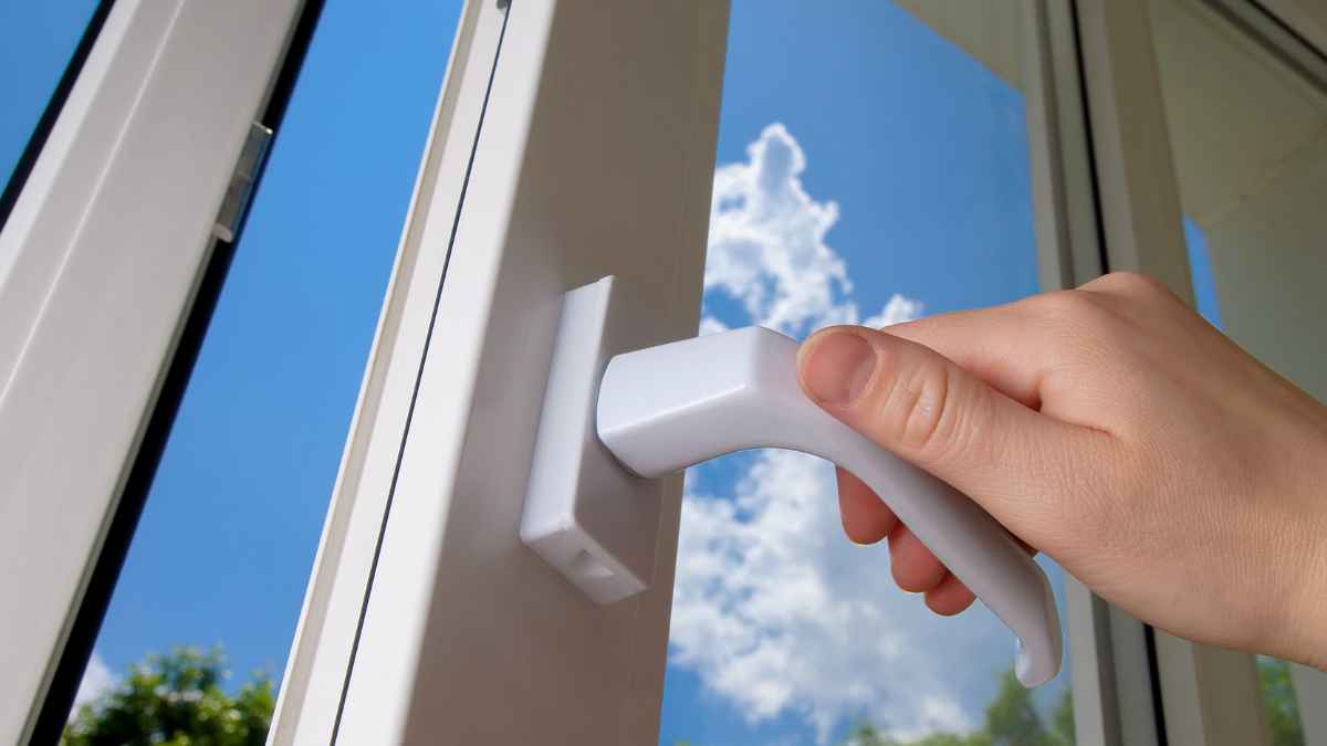 Una persona abre una ventana para ventilar la vivienda durante una noche de calor siguiendo las recomendaciones de la AEMET.