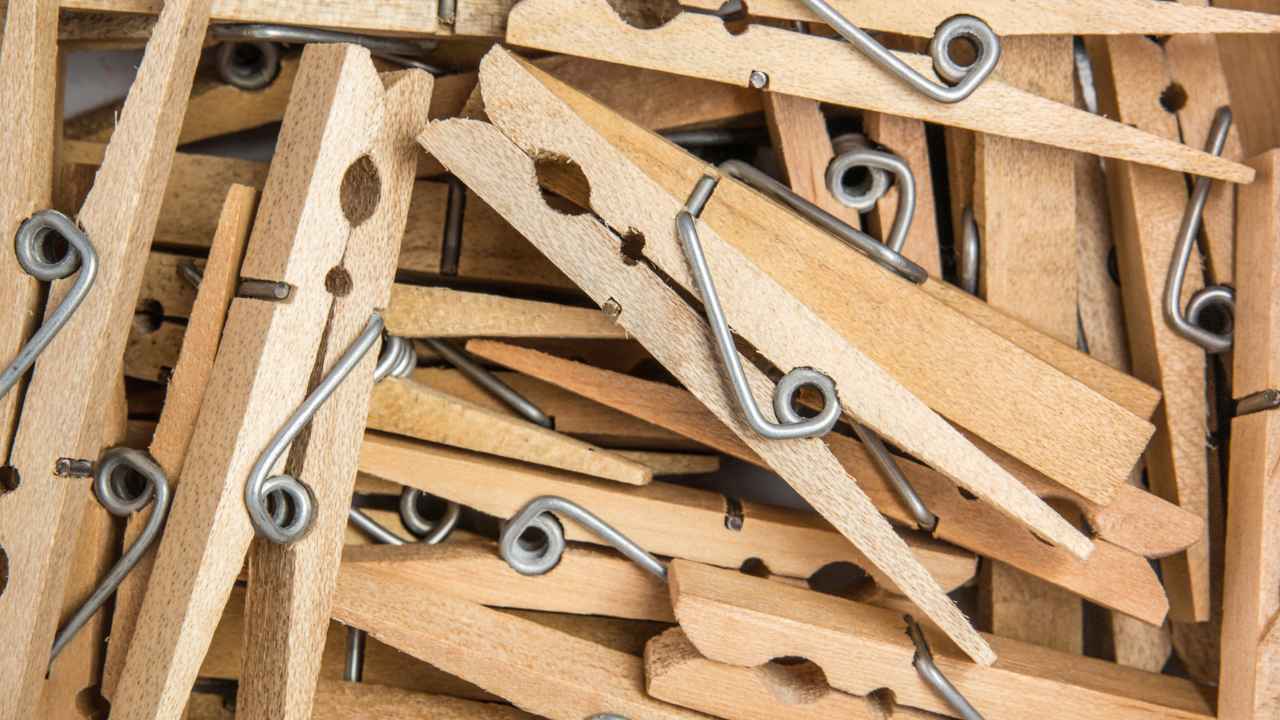 Primer plano de una pinza de madera donde se distinguen sus dos cavidades y el muelle metálico.