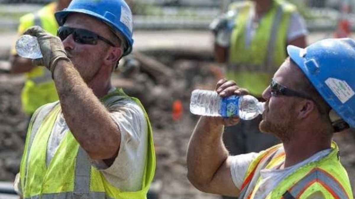 Albañiles beben agua durante una jornada de trabajo con calor extremo para prevenir golpes de calor en una obra.
