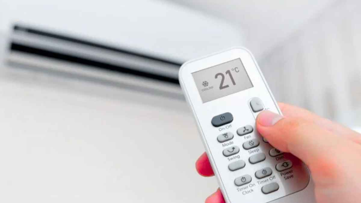 Persona ajustando el aire acondicionado con un mando a distancia para reducir el consumo eléctrico en verano