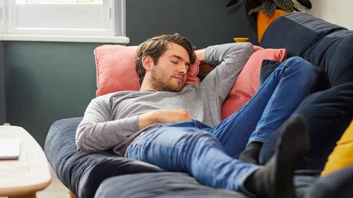 Hombre durmiendo una siesta en el sofá para mejorar la memoria, el aprendizaje y el rendimiento según un estudio científico