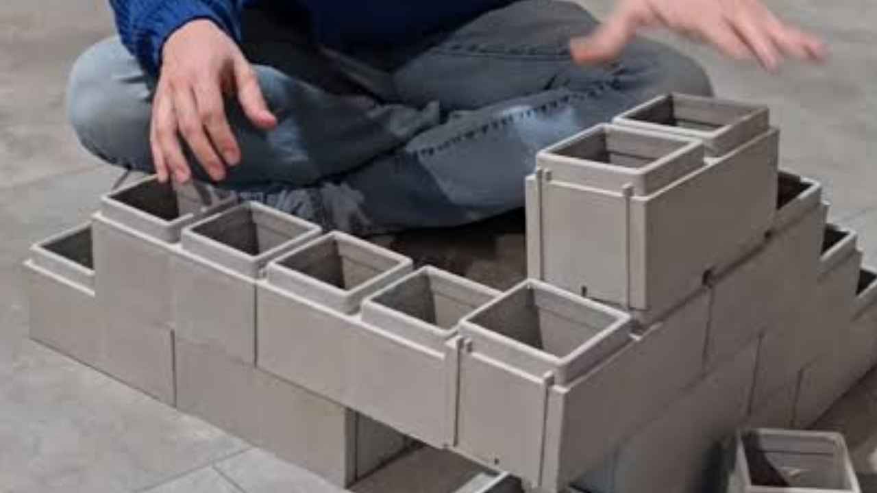Hombre construyendo una maqueta con ladrillos modulares de plástico reciclado tipo Lego.