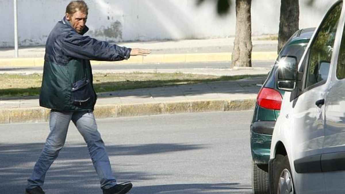 Un gorrilla indica una plaza de aparcamiento a un conductor en una calle mientras la Policía alerta de cobros ilegales en Matalascañas.