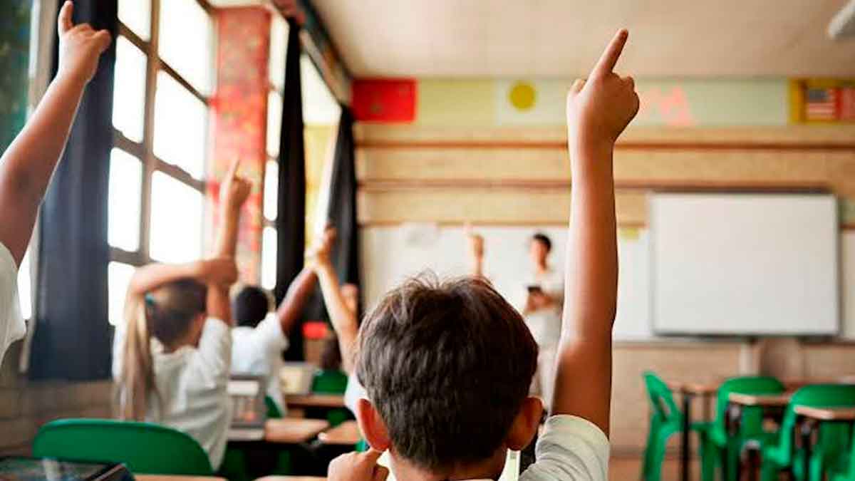 Alumnos levantan la mano en un aula durante una clase en un centro educativo