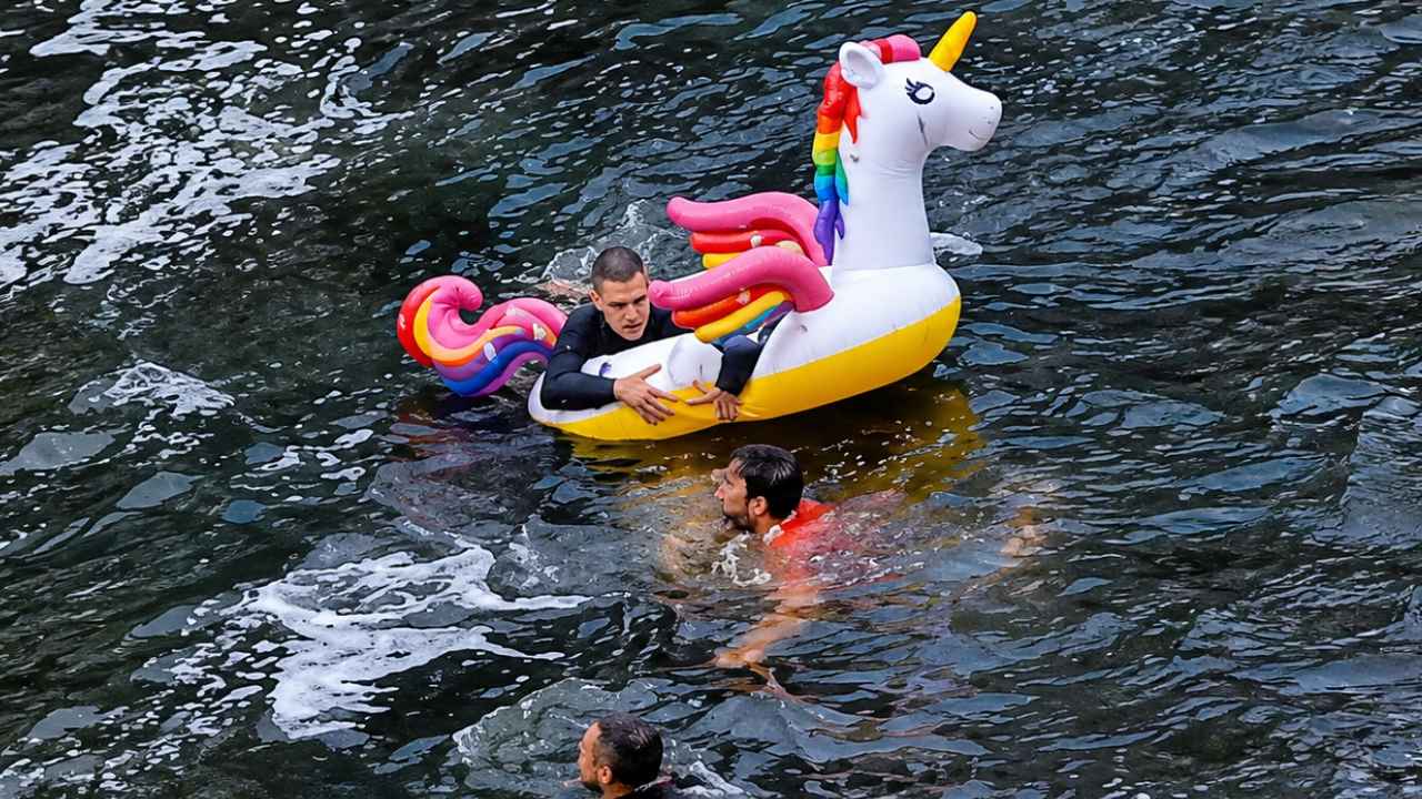 Tres jóvenes en el río Deba junto a un flotador hinchable con forma de unicornio