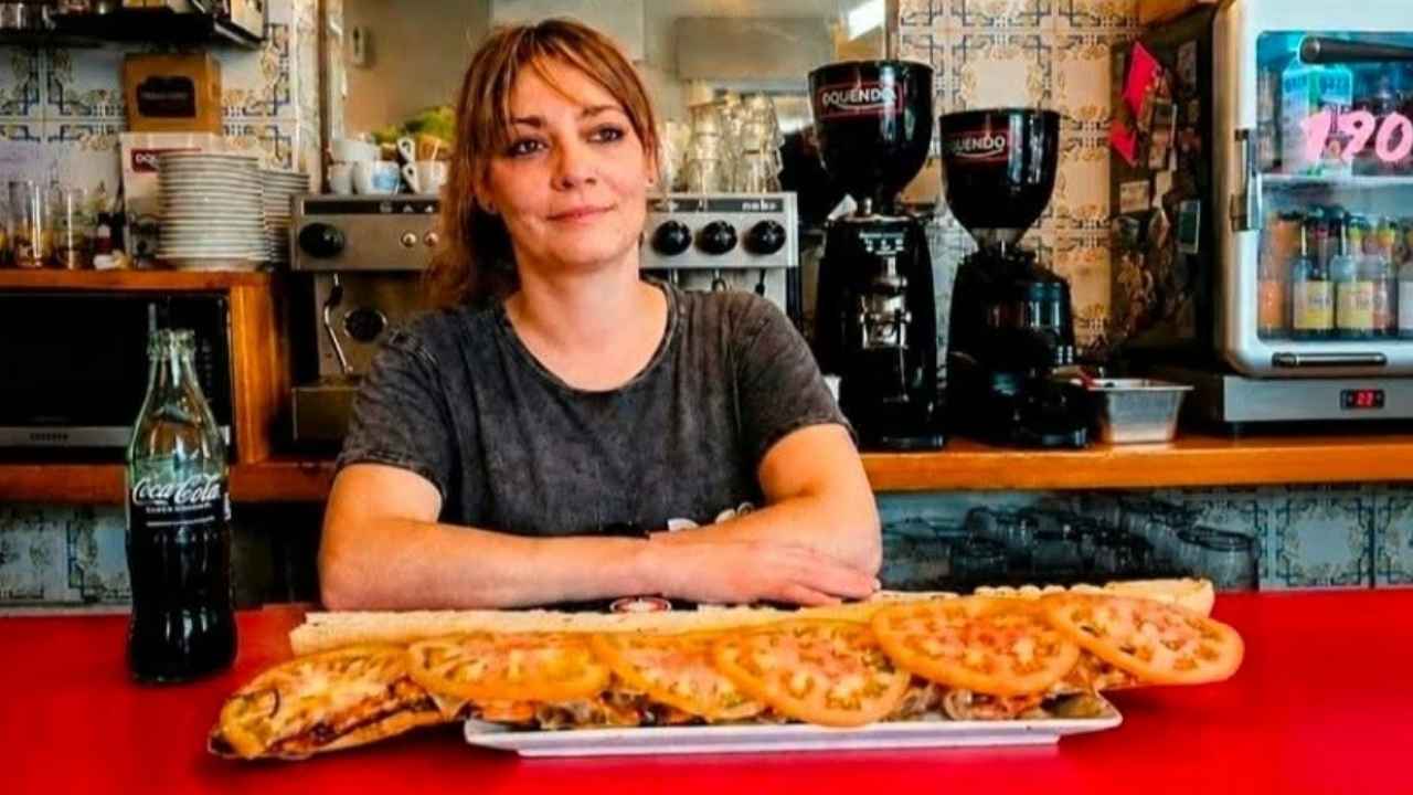 María, dueña del Bar La Revuelta, junto a un bocadillo de medio metro