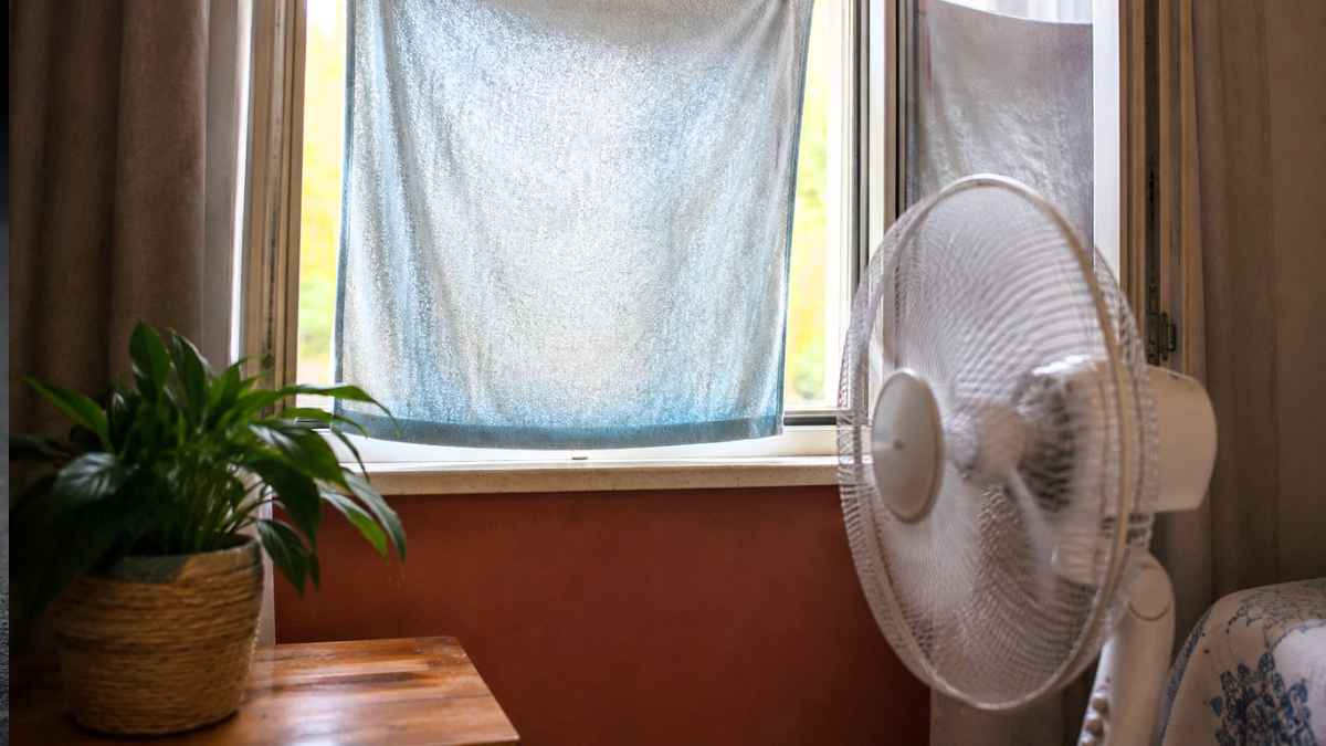 Toalla húmeda colocada frente a una ventana abierta para enfriar la casa sin aire acondicionado durante una ola de calor.