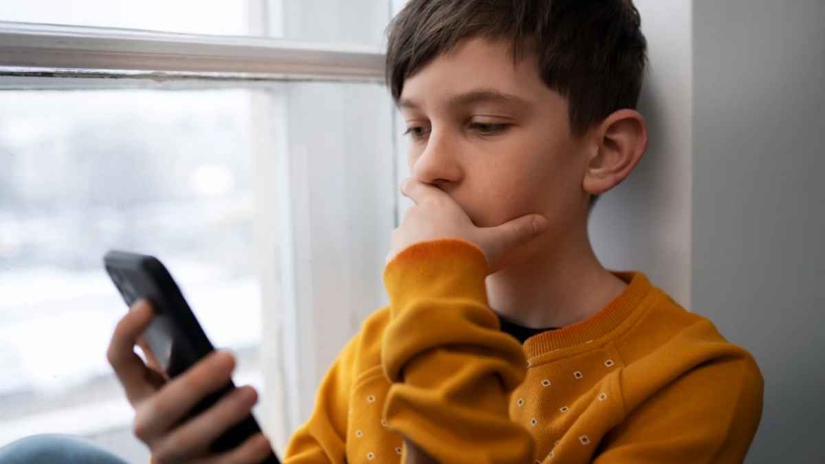 Niño mirando un teléfono móvil antes de los 13 años, una práctica asociada a un mayor riesgo de problemas de salud mental según un estudio