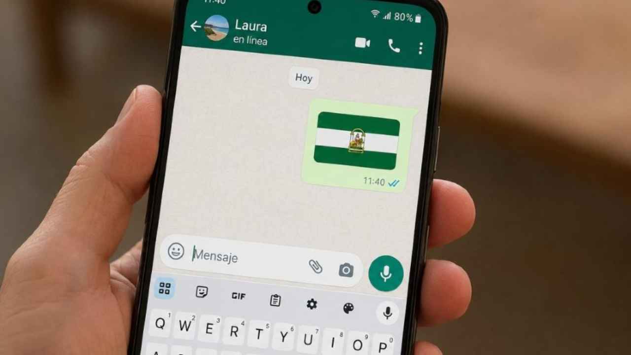 Bandera de Andalucía junto a un teléfono móvil con el teclado de emojis abierto.