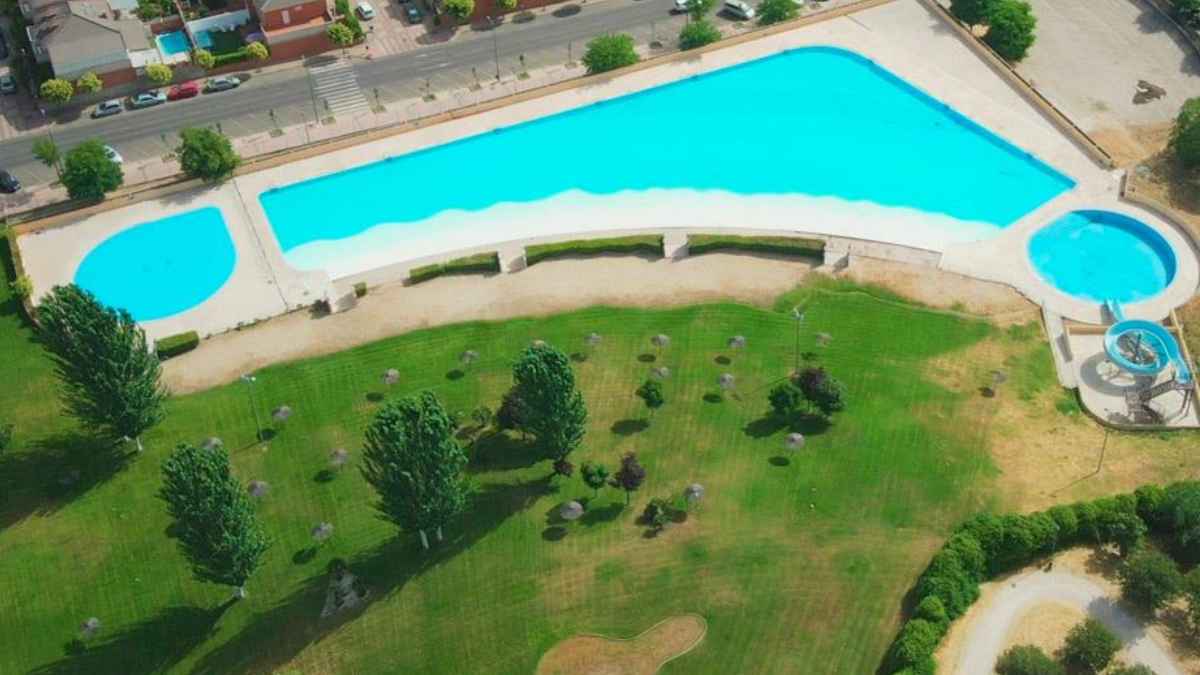 Vista aérea del complejo de piscinas de agua salada de Parla con zona de arena, tobogán y amplias áreas verdes.