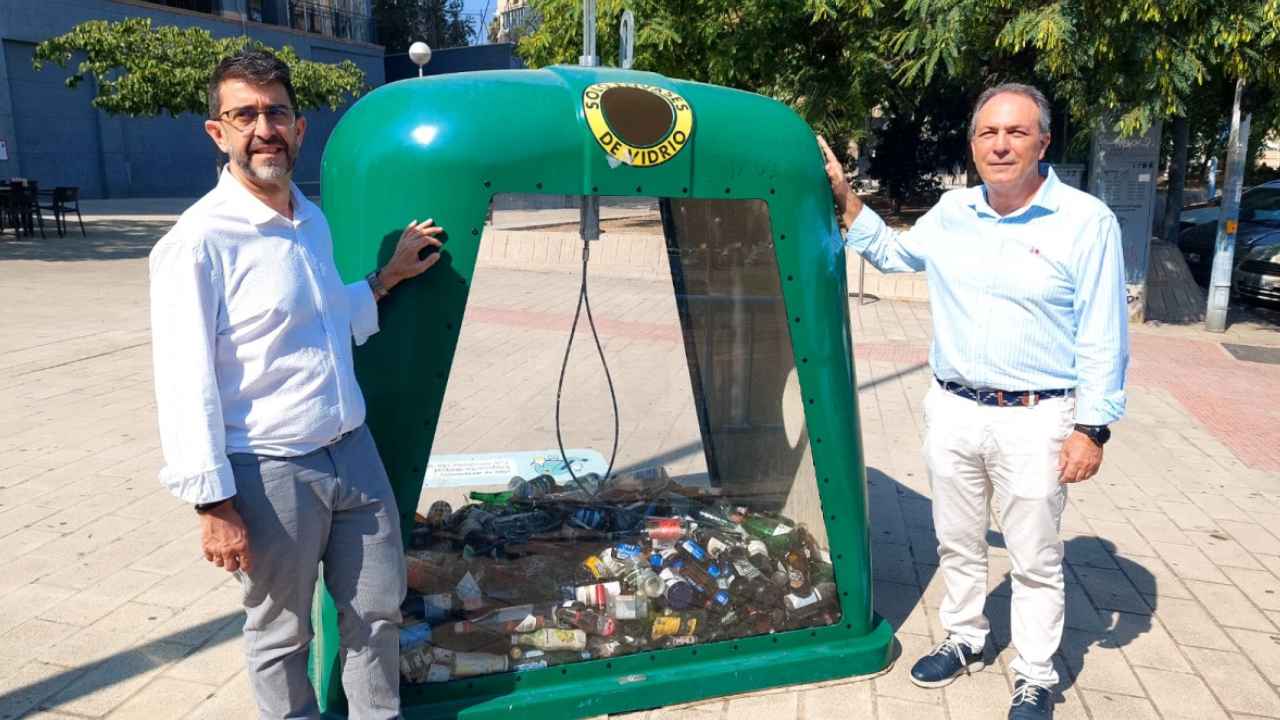 Dos representantes junto al primer contenedor transparente para envases de vidrio instalado en Alicante.