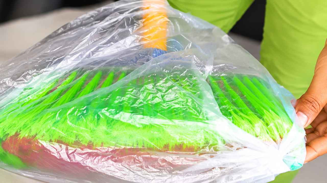 Bolsa de plástico colocada sobre las cerdas de una escoba para recoger pelos y pelusas del suelo.