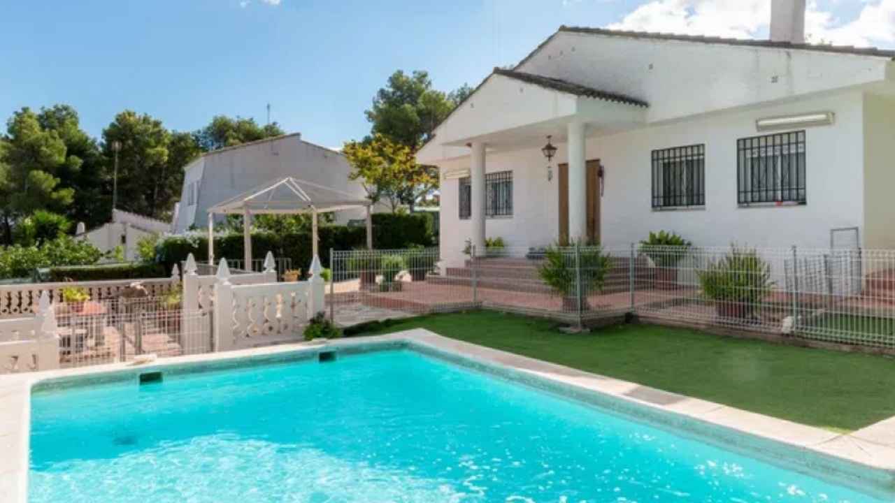 Casa rural de piedra con jardín y una barbacoa exterior.