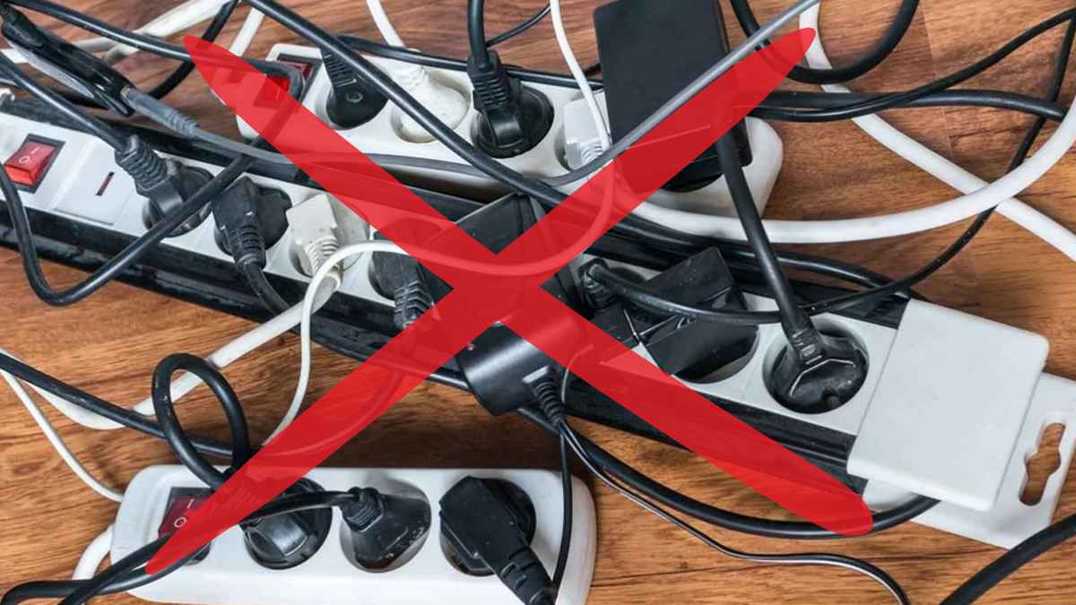 Varias regletas eléctricas sobrecargadas de enchufes y cables con una cruz roja