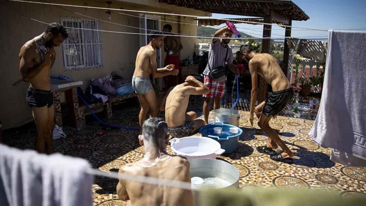 Migrantes se asean con cubos de agua en la terraza de la casa de Sabah en Ceuta