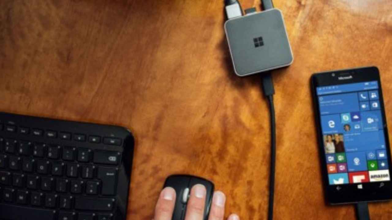 Persona utilizando un smartphone junto a un ordenador portátil en casa.