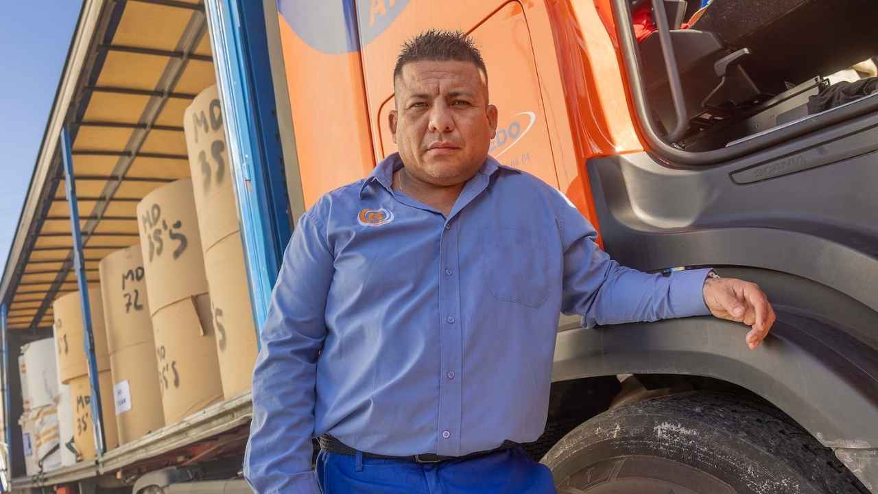 Camionero junto a un camión de transporte de mercancías durante su jornada laboral