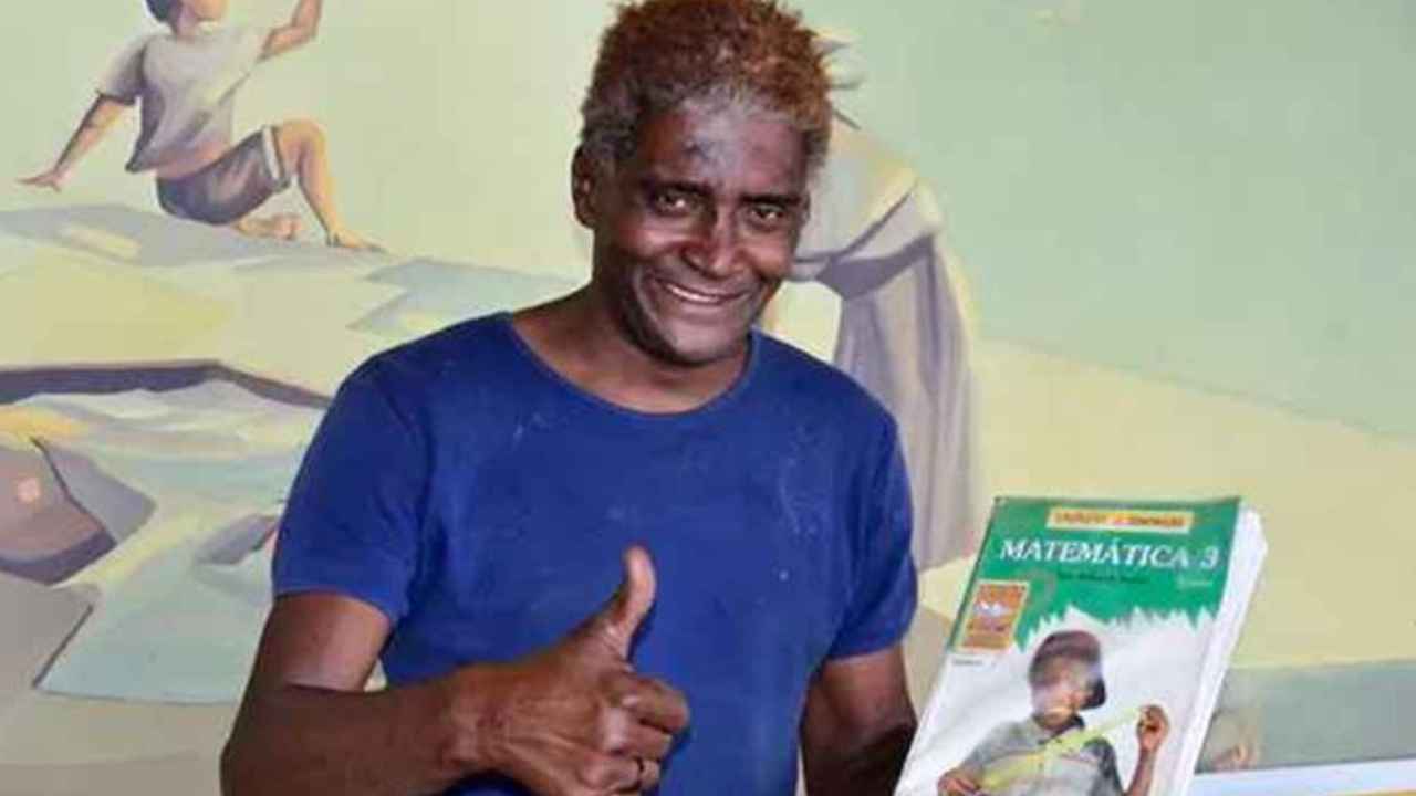 Hombre sonriente sostiene un libro tras superar un concurso municipal en Patos de Minas