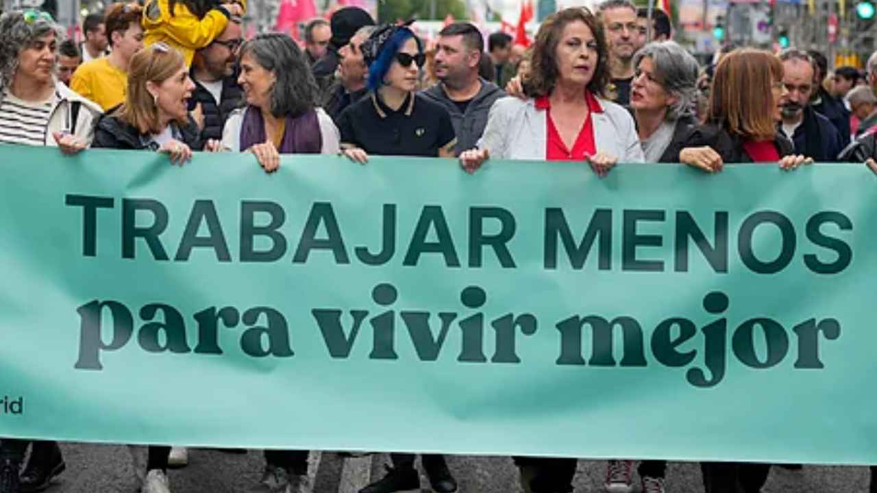 Manifestación en Madrid por la reducción de la jornada laboral con una pancarta que pide trabajar menos