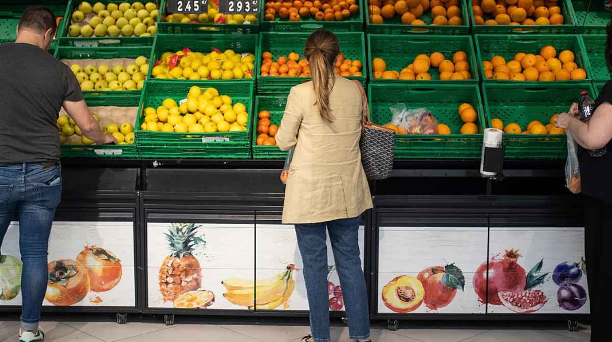 Clientes comprando fruta en la sección de frescos de un supermercado