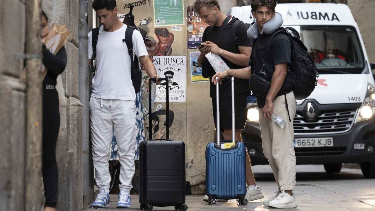 Turistas con maletas entrando en un edificio residencial con viviendas de alquiler turístico.