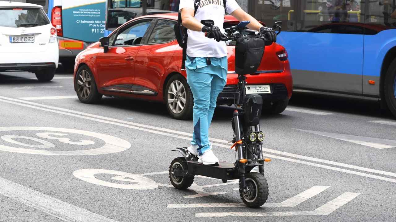 Usuario circulando en patinete eléctrico por una calle urbana con tráfico